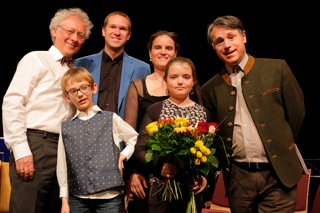 Alma mit Blumen, dahinter ihre Mutter Antonia, rechts im Bild der Dirigent, links der Komponist mit seinem Sohn Oskar